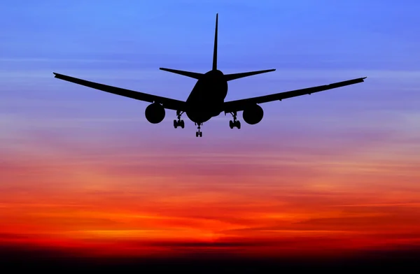 Siluett kommersiella flygplan flyger på sunset — Stockfoto
