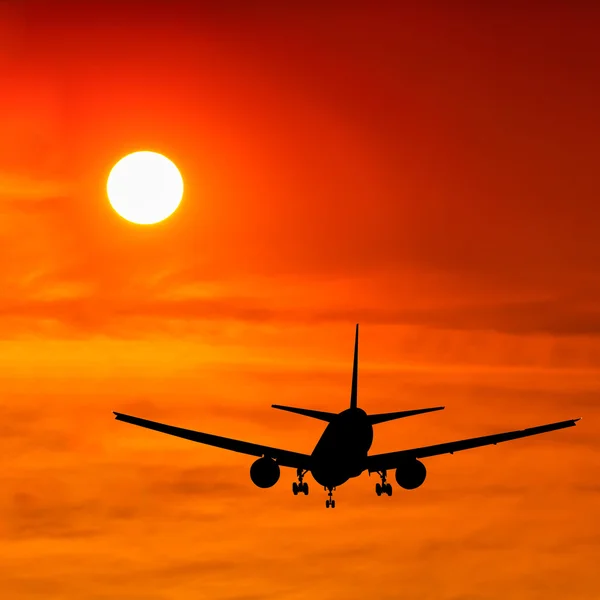 Siluett kommersiella flygplan flyger på sunset — Stockfoto