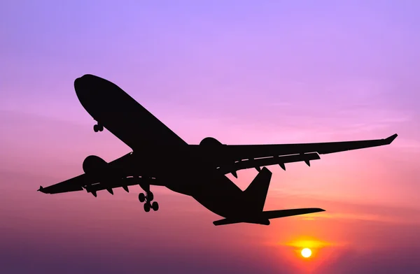 Avión comercial Silhouetted volando al atardecer — Foto de Stock
