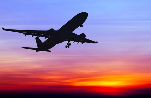 Siluett kommersiella flygplan flyger på sunset — Stockfoto