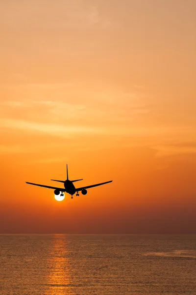 सूर्यास्त पर समुद्र के ऊपर उड़ान भरने वाले सिल्हूटित वाणिज्यिक विमान — स्टॉक फ़ोटो, इमेज