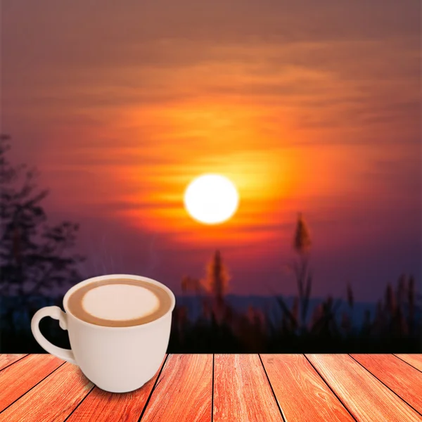 Káva v šálku bílé keramiky na prkno dřeva s východem slunce poza — Stock fotografie