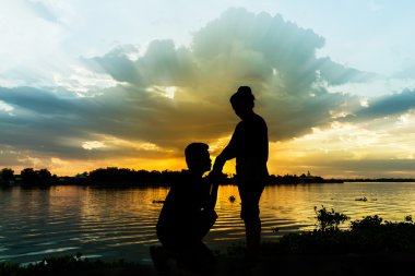 Güzel gün batımı ile nehrin yanında çift silüeti