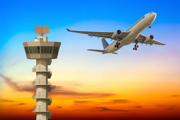 Verkehrsflugzeug hebt bei Sonnenuntergang über Flughafen-Kontrollturm ab — Stockfoto