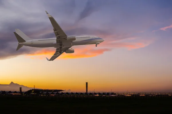 Ticari uçak havaalanında üzerinde günbatımında uçan — Stok fotoğraf
