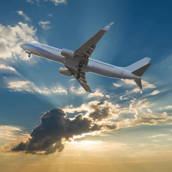 Commercial airplane flying with clouds and sun rays background — Stock Photo, Image