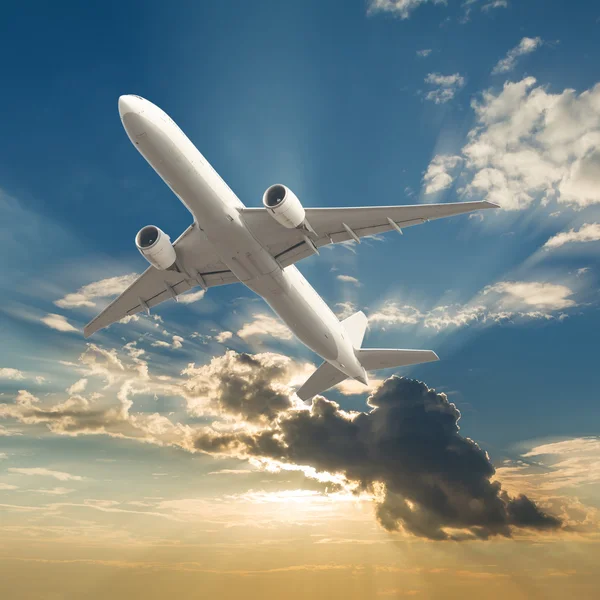Verkehrsflugzeug fliegt mit Wolken und Sonnenstrahlen im Hintergrund — Stockfoto