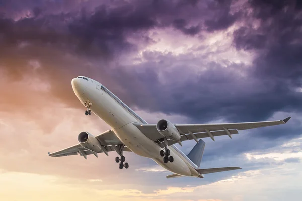Avião comercial voando ao pôr do sol com nuvens de tempestade backgroun Imagens De Bancos De Imagens