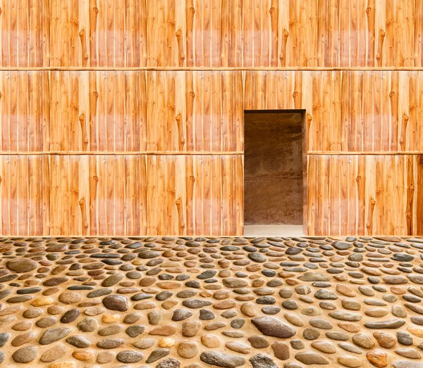 Wooden wall with door and stone floor in front off — Stock Photo, Image