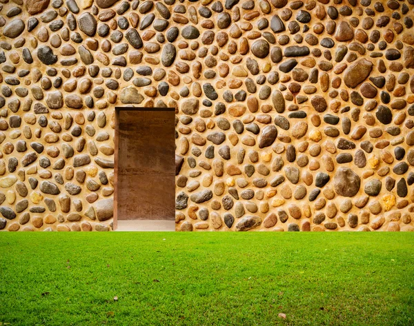 Pared de piedra con puerta y suelo de hierba en frente — Foto de Stock