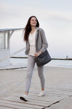 Şık rahat giyim gün batımında sahilde poz bir kızın moda portre. Genç kadın açık havada