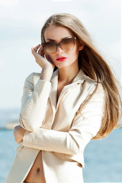 夏天的眼镜和豪华轻型夹克和短裤在海和天空的背景上优雅的女孩画像 — 图库照片