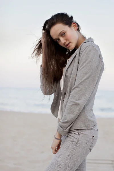 Fashionabla porträtt av en flicka som poserar på stranden vid solnedgången i en snygg bekväma kläder. Ung kvinna utomhus — Stockfoto