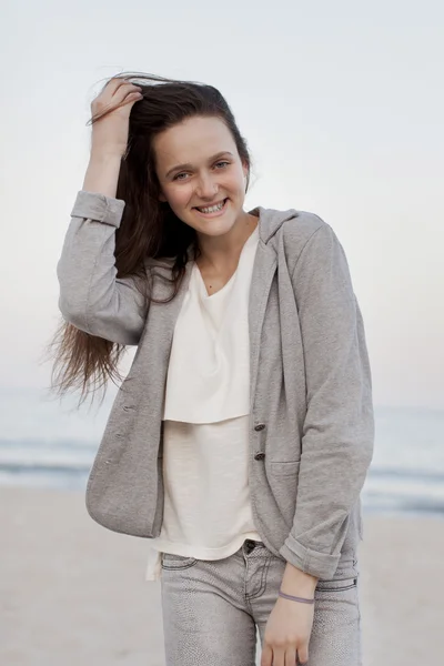 Modieuze portret van een meisje die zich voordeed op het strand bij zonsondergang in een stijlvolle comfortabele kleding. Jonge vrouw buitenshuis — Stockfoto