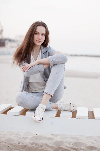 Portrait à la mode d'une fille posant sur la plage au coucher du soleil dans un élégant vêtement confortable. Jeune femme en plein air — Photo