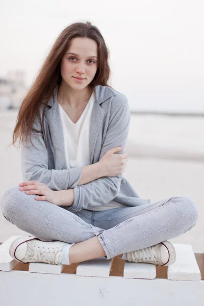 Fashionabla porträtt av en flicka som poserar på stranden vid solnedgången i en snygg bekväma kläder. Ung kvinna utomhus — Stockfoto