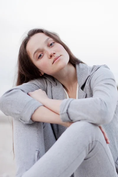 Fashionable portrait of a girl posing on the beach at sunset in a stylish comfortable clothing. Young woman outdoors — Stock Photo, Image