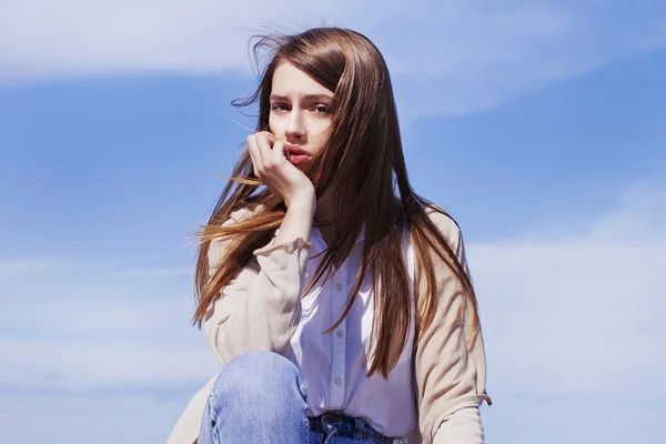 Krásná dívka s dlouhými tmavými vlasy v jednoduchých šatech sedí — Stock fotografie