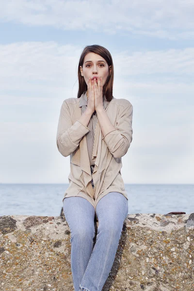 Beautiful girl with long dark hair in a simple dress sits — Stock Photo, Image