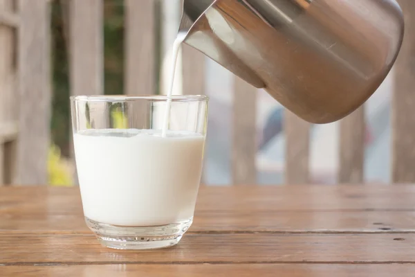 Pour milk from a pitcher into a glass — Stock Photo, Image