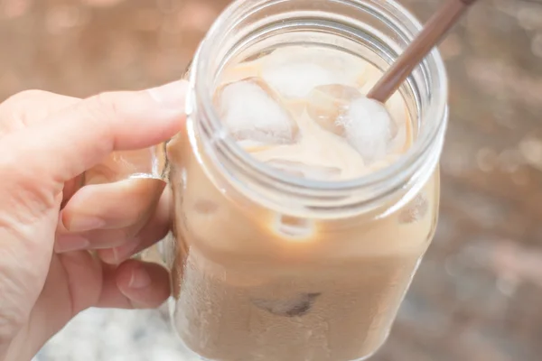 Hand on glass of iced milk coffee with vintage filter effect — Stock Photo, Image