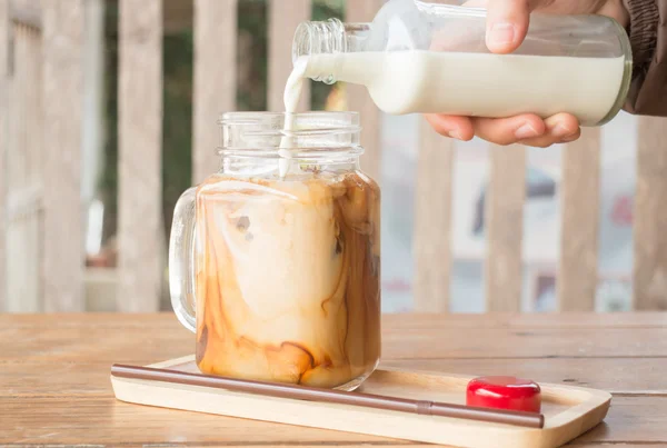 Derramando leite para vidro gelado de café — Fotografia de Stock