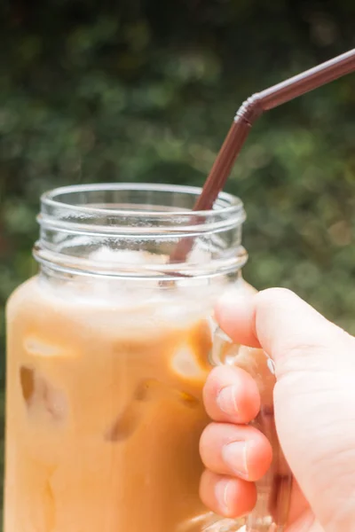 Рука на стакане кофе со льдом молока с эффектом винтажного фильтра — стоковое фото
