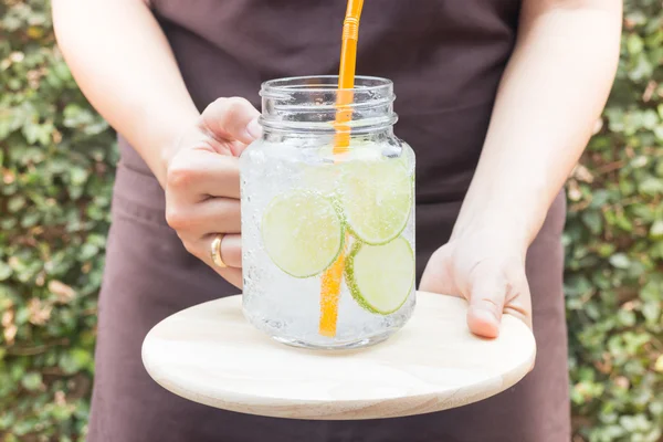 Hand op glas van iced kalk frisdrank drank serveren — Stockfoto