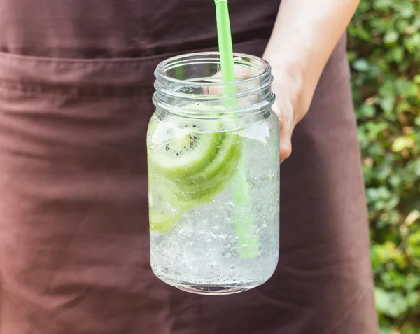 Main sur le verre de service de boisson gazeuse glacée kiwi — Photo