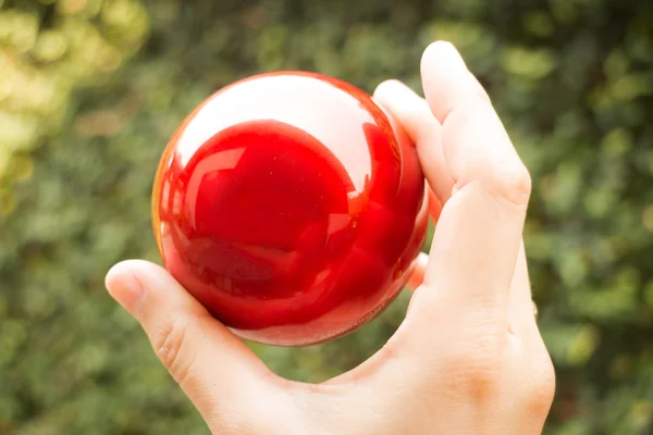 Shiny red ball on hand — Stock Photo, Image