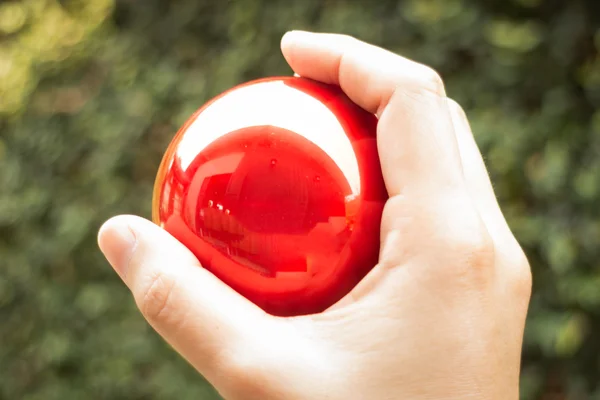 Shiny red ball on hand — Stock Photo, Image