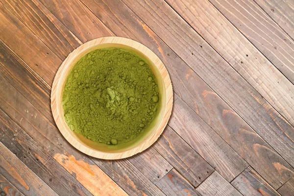 Tigela de madeira de chá verde em pó no fundo textura de madeira — Fotografia de Stock