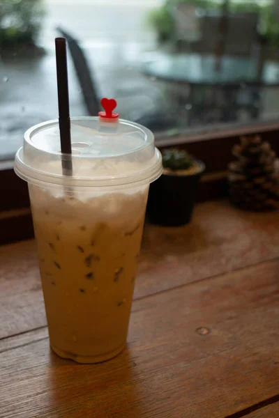 木製テーブルの上の使い捨てカップに氷のミルクコーヒー ストックフォト — ストック写真