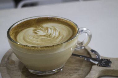 Bir fincan sıcak kahve, yanında sanat eseri ve fotoğraf.