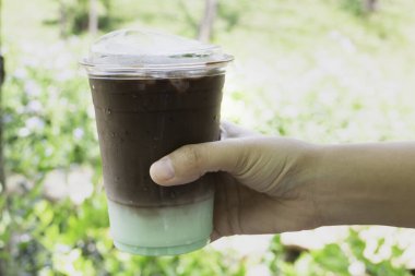 Tek kullanımlık kahve bardağında buzlu kahve içen kadın.