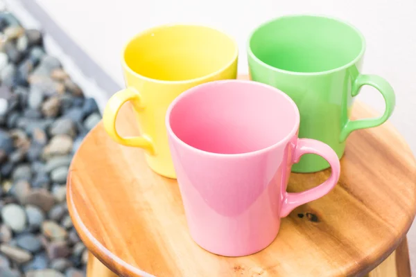 Vacker färg mugg koppar på träbord — Stockfoto