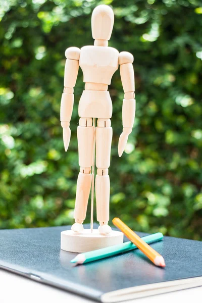 Wood mannequin standing on artist work paperbook — Stock Photo, Image