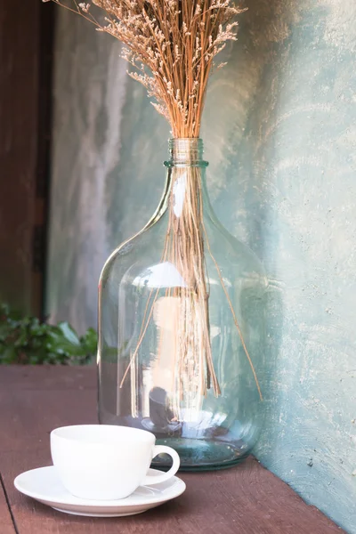 Xícara de café e vaso de flores secas na mesa de madeira — Fotografia de Stock