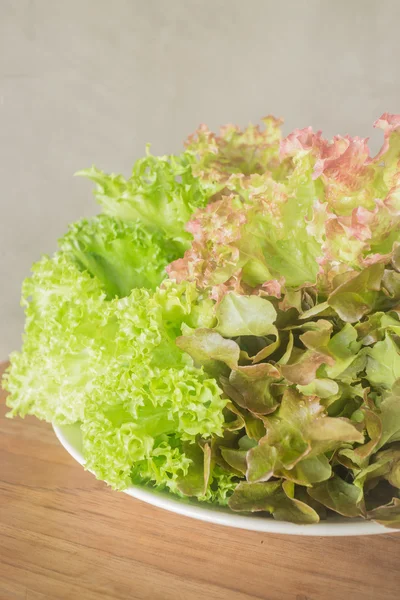 Frisches Salatgemüse auf hölzernem Hintergrund — Stockfoto