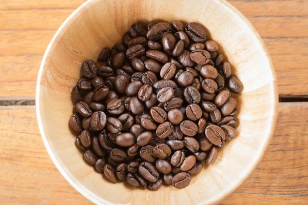 Жареные кофейные зерна в деревянной миске — стоковое фото