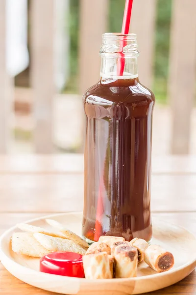 Sebotol kopi es hitam dengan beberapa makanan ringan — Stok Foto