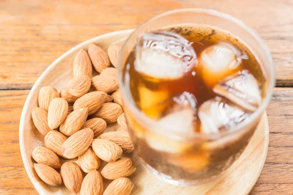 Glass of black iced coffee with almond grain — Stock Photo, Image