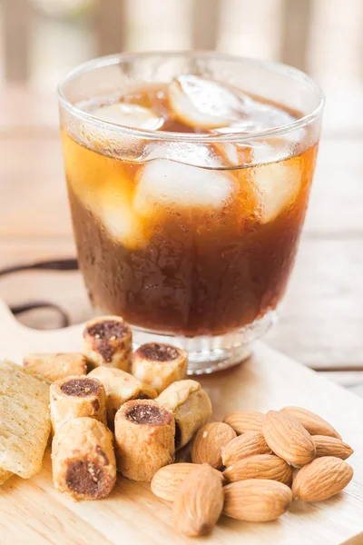 Un vaso de café helado negro con algo de merienda —  Fotos de Stock