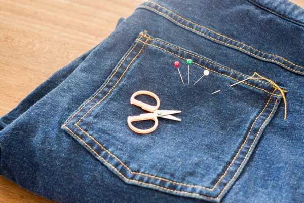 Needle with a thread through the jean