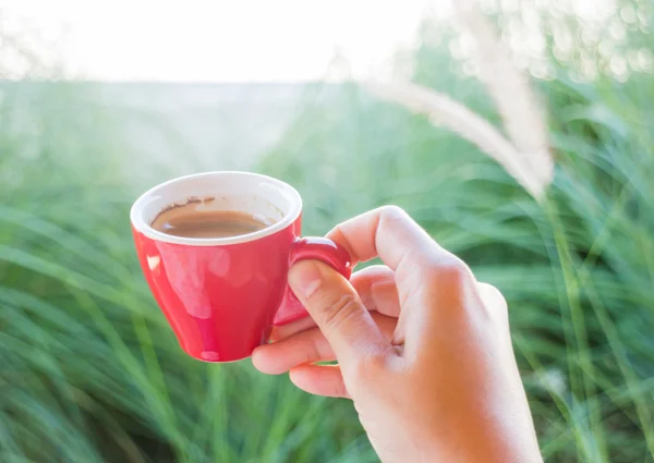 Frau hält eine rote Kaffeetasse in der Hand) — Stockfoto