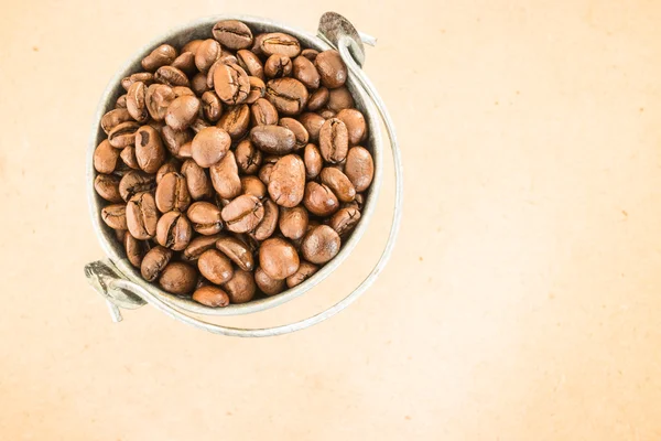 Káva pražená bean v kbelíku na dřevěné pozadí — Stock fotografie