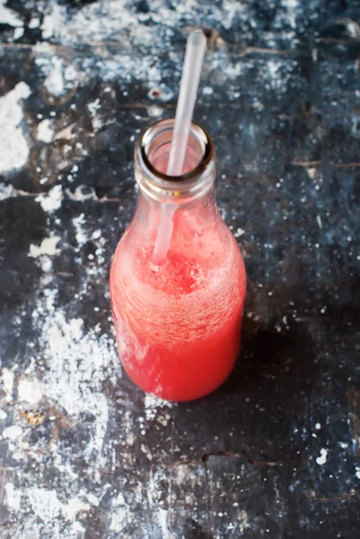 Suyu güler yüzlü şişe kırmızı meyve eski püskü arka plan