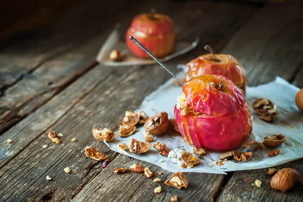 Červené pečené jablka plné vlašské ořechy dřevěný stůl — Stock fotografie
