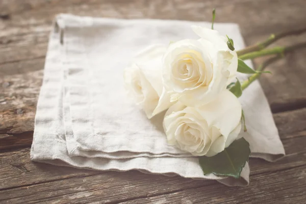 Tres rosas blancas en servilleta de lino y mesa de madera. Vintage —  Fotos de Stock