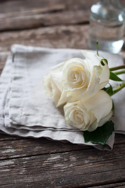 Drei weiße Rosen auf Leinenserviette und Holztisch. Jahrgang — Stockfoto